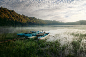 The boat is parked by the lake in the morning at Danau Tamblingan .
