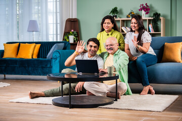 Happy indian family using laptop while sitting on sofa at home.