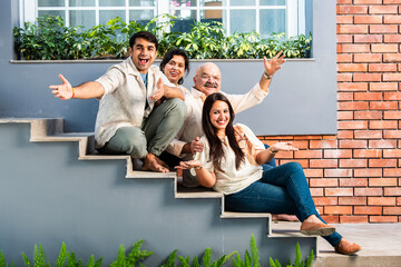 Outdoor portrait of cheerful Indian family sitting on stairs.