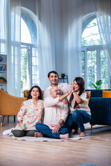 Portrait of happy Indian family of four sitting in modern living room