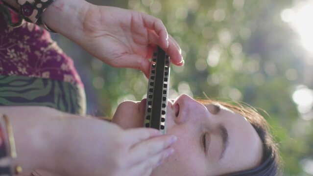 vertical shot. young girl plays the harmonica in the forest. the girl loves to play the harmonica. girl in the forest.