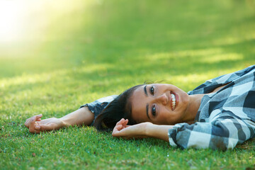 Space, portrait or happy woman on lawn to relax for rest in park, nature or field for peace in USA. Flare, travel or female person on break with smile on outdoor summer vacation or holiday on grass