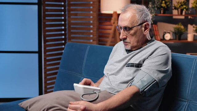 Aged man taking blood pressure by modern equipment for self-examination and control of hypertension