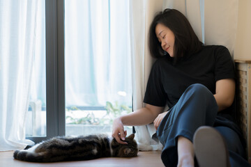 wellness and wellbeing concept with asian woman sit and play with her cat in livingroom
