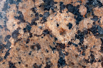Grainy dark brown background with black spots. Texture backdrop with small crumb pattern for interior design and kitchen countertop. Imaginary face trapped in stone