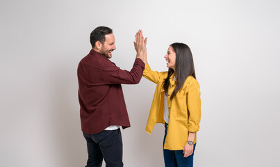 Cheerful young couple shouting and giving high-five while enjoying success over white background