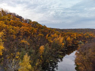 Fototapeta premium Autumn aerial river valley and colorful golden forest. Flying above autumnal riverside in Ukraine