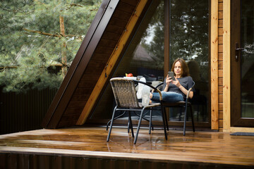 Cute woman with smartphone on terrace of her a-frame house
