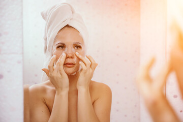 Young beautiful woman using a moisturizing facial mask after taking a bath. Pretty attractive girl...