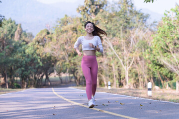 Young Asian woman jogging in the morning at a public park on a bright sunny day.