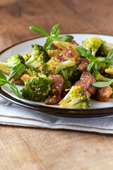 Duck and Broccoli Stir-Fry (with soy sauce and sesame oil). Wooden background. Close up.	