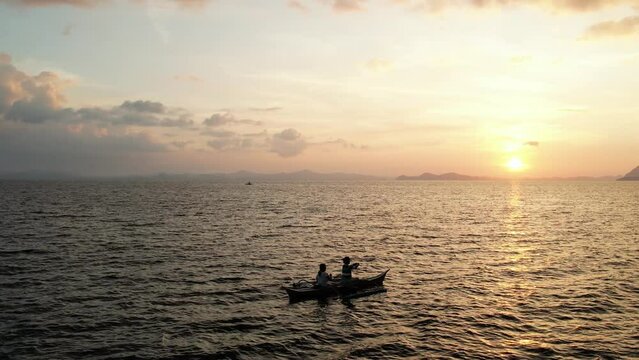 Pêcheurs sur une barque au coucher de soleil