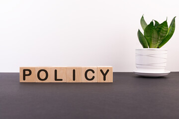 POLICY word on wooden cubes on a dark table with flower and light background