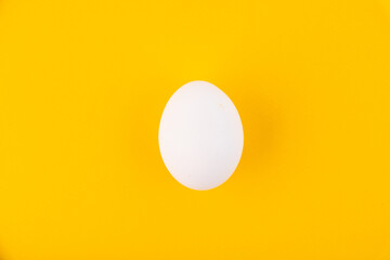 White egg on the yellow background in center. Design, visual art, minimalism