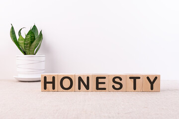 HONESTY word on the concept of building blocks on a light table with a flower and a light background