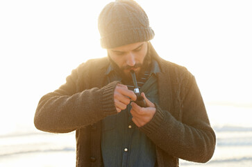 Smoker, man and lighting a pipe in outdoor, relax and sailor habit on winter morning in sunrise....