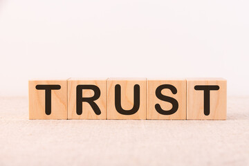 Trust word concept written on wooden cubes on a light table and a light background