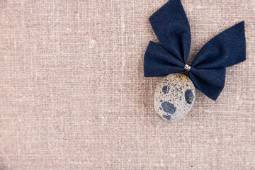 Fototapeta premium Easter composition with egg and bow on a linen surface.