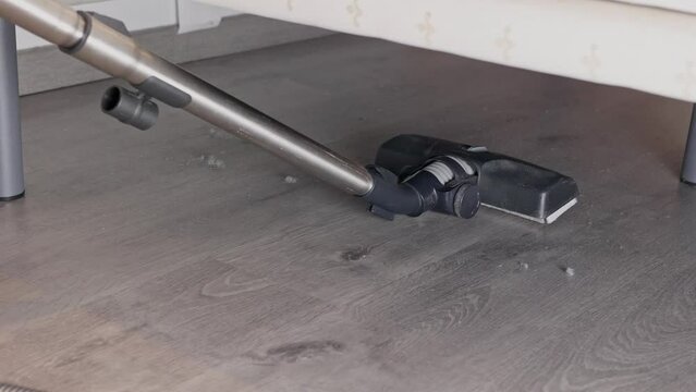Cleaning dust under the bed with a vacuum cleaner. A lot of dust has accumulated on the floor under the bed.