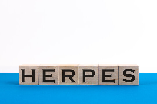 Herpes - word from wooden blocks with letters, viral diseases herpes viruses concept, random letters around, blue background