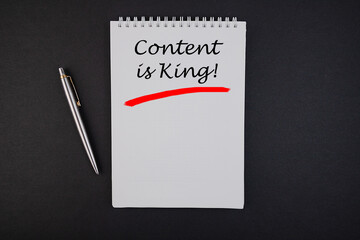 The inscription in the notebook Content is king on a black table.
