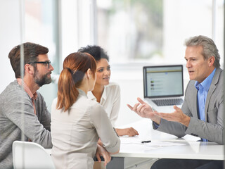 Naklejka premium Senior businessman, meeting and discussion with team in finance or coaching with documents at office. Man, CEO or executive talking to group of employees for financial growth or revenue at workplace