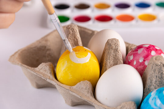 Easter, holidays, tradition and people concept - close up of woman hands coloring easter eggs with brush