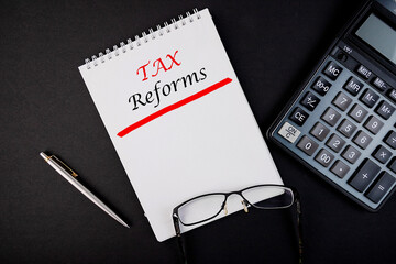 Tax reform concept written in a notebook with pen and calculator.