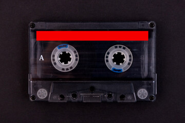 Retro audio cassette tape from the 80s on a black background.