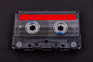 Retro audio cassette tape from the 80s on a black background.