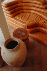 Bright orange sofa and vintage brown clay vase in a boho interior