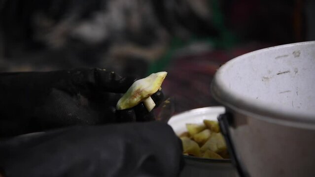 Close-up view of person in black gloves cleaning Suillus luteus (also known as slippery jack or sticky bun) edible mushrooms using knife in dark room. Soft focus. Real time handheld video. Food theme.