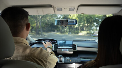 Back view of beautiful young couple driving comfortable automobile on a country road. Travel and vacation concept