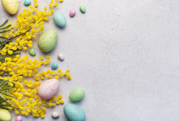 Pastel Easter Eggs and Yellow Mimosa Flowers on a Light Grey Background