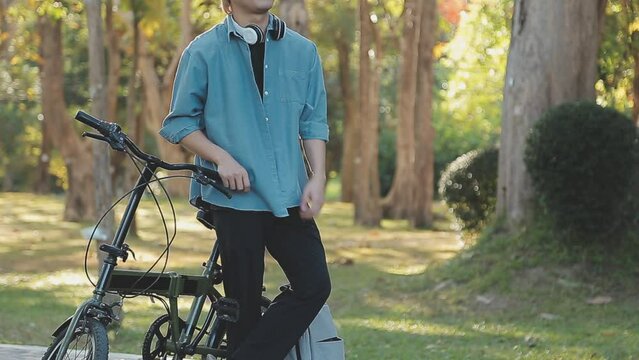 Portrait of a happy young man dressed in shirt with bag riding on a bicycle outdoors