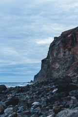 cliffs of massive rocks near the black beach with moody ocean