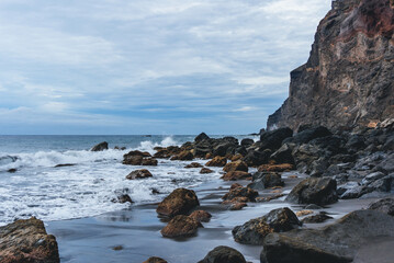 Fototapeta na wymiar rocky coast of the atlantic ocean in moody atmosphere with black sand beach and waves 