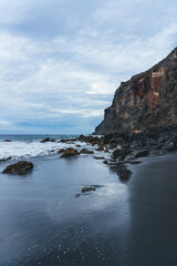 Fototapeta na wymiar rocky coast of the atlantic ocean in moody atmosphere with black sand beach and waves 