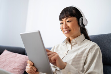 Beautiful Korean woman using tablet computer at home.