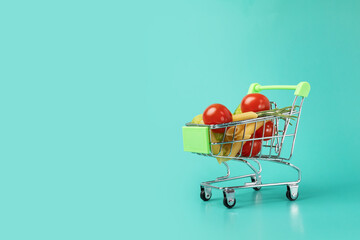 Shopping basket with groceries, green background, fresh and organic products, supermarket Trolley filled with food ingredients