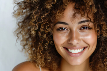Confident young woman with curly hair smiling at camera. Beauty and self-confidence.