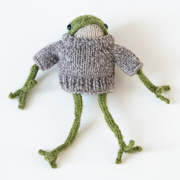 Knitted green frog in a brown sweater