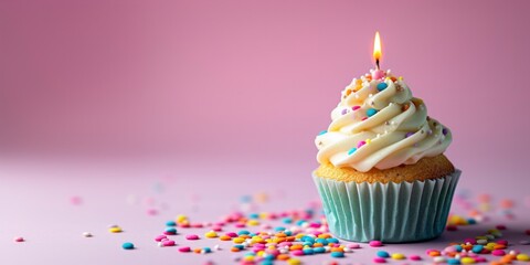 A vanilla cupcake with vibrant frosting and lit candle on a pink background.