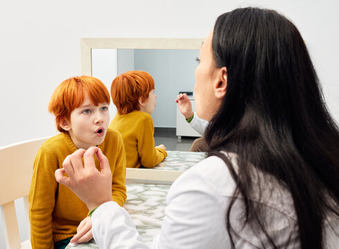 Treatment of stuttering in children. Speech and language therapist doing articulation and breathing exercises with boy patient