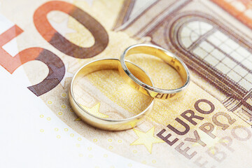 Wedding rings on money. Cost of wedding. Price of getting married background. Golden jewelry on banknote. Expensive marriage. Fifty euro note. Gold price background.