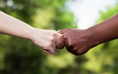 Two hands of different skin colors holding hands