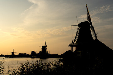 Windmills silhouettes in the beautiful village of Zaanse Schans in Netherlands at sunset