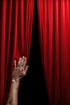 A hand reaching out from behind a vibrant red curtain. Perfect for adding an element of surprise or mystery to your design projects