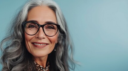 Obraz premium Woman with gray hair wearing glasses smiling against blue background.