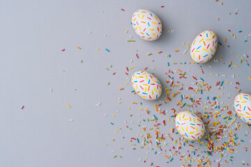 Sprinkle painted colourful easter eggs on grey background.